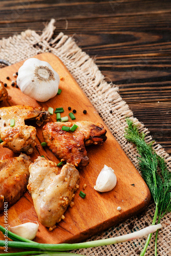 
baked chicken wings and garlic marinade with herbs on a wooden background