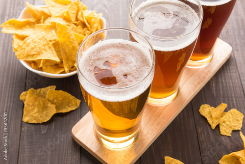 Assortment of beer glasses with nachos chips on a wooden table