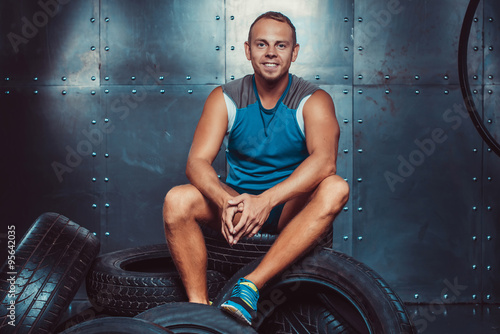 Sportsman sitting on the tire machine. Concept of CrossFit, health and strength.