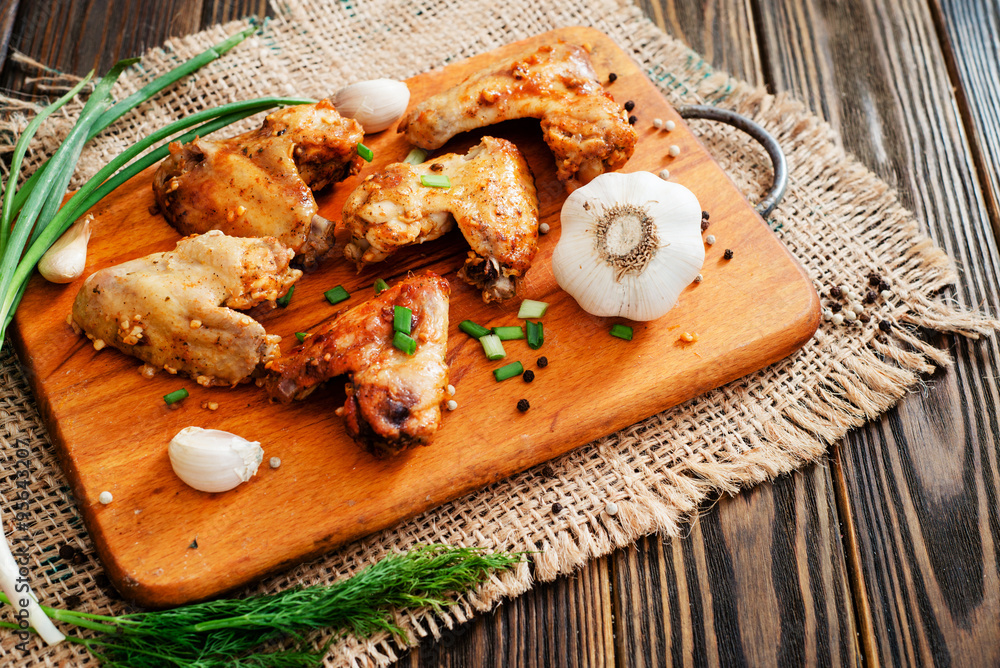 
baked chicken wings and garlic marinade with herbs on a wooden background