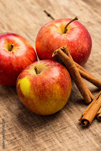 Rote Äpfel mit Zimt vor Holz-Hintergrund