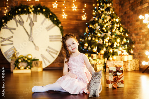 Little girl with a cat in a holiday room