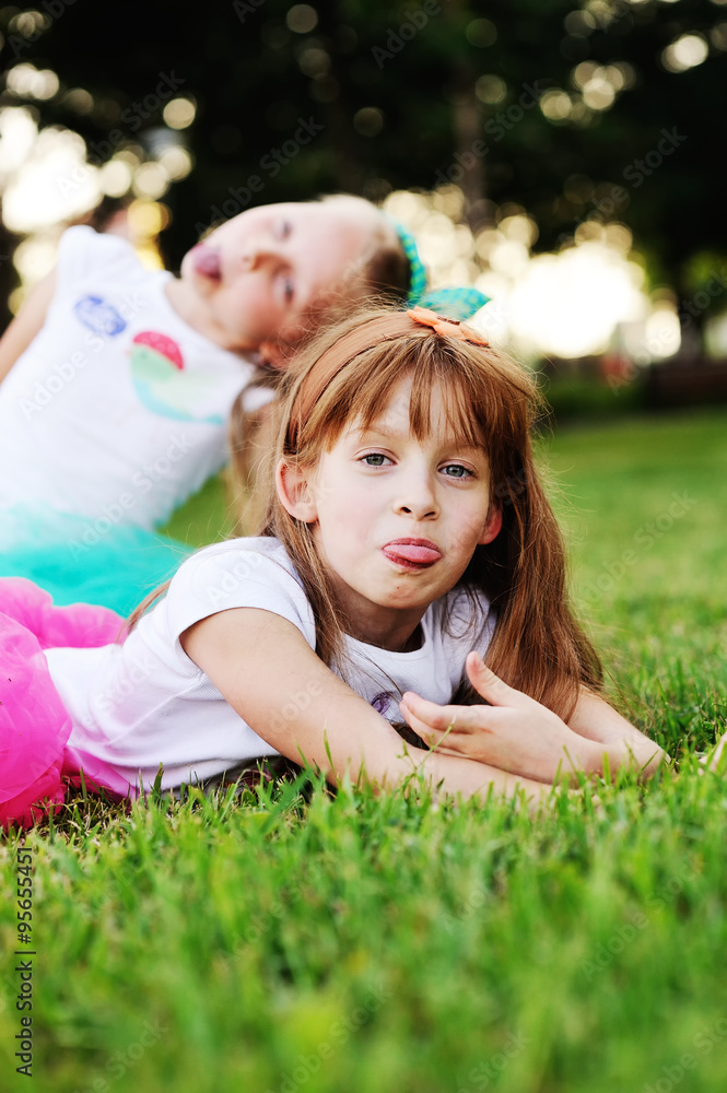 two little girls grimace on the grass background two little girls grimace on the grass background