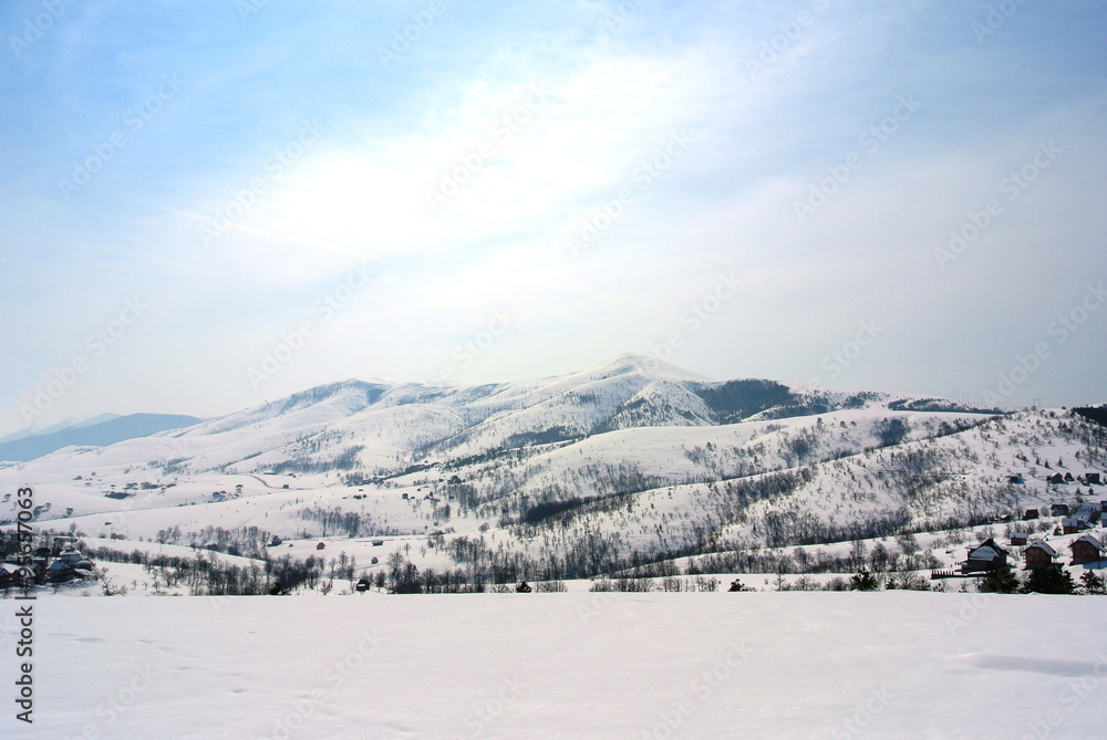 Beautiful, idyllic snowy winter landscape in the mountains, on a crisp sunny morning; hills and slopes; nature.