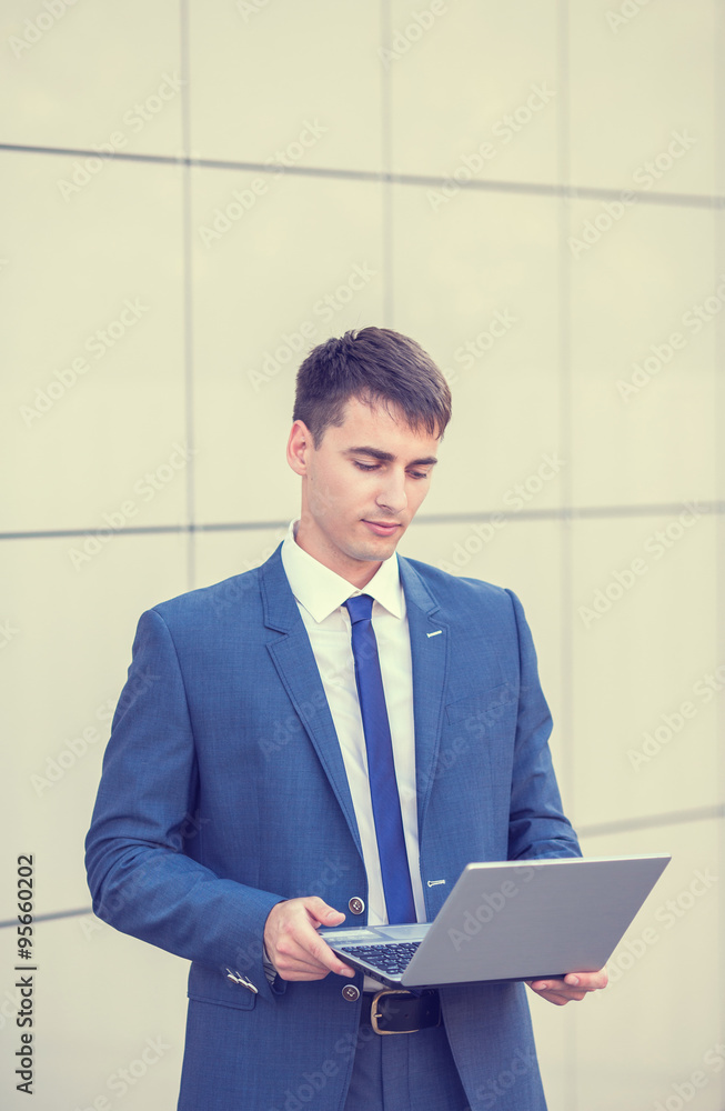 Successful businessman standing in the street holding a laptop Successful businessman standing in the street holding a laptop