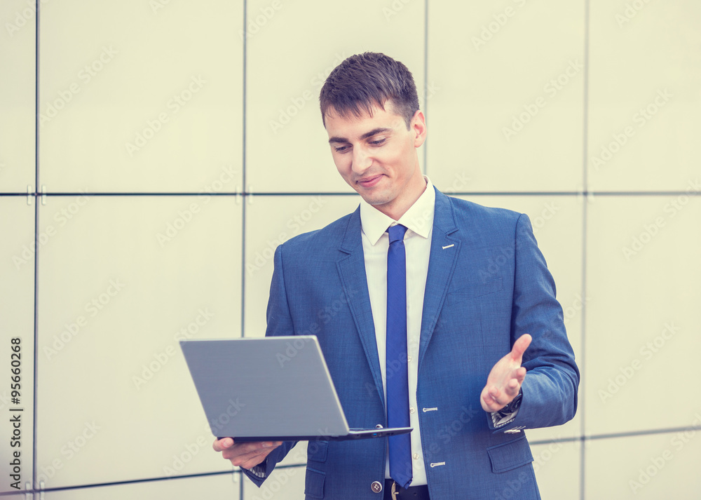 Successful businessman standing in the street holding a laptop Successful businessman standing in the street holding a laptop