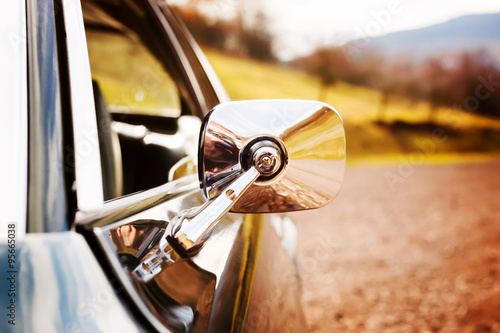 Closeup view on a chrome mirror of a classic car photo