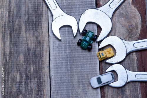 Fotografija little toy cars near the wrenches on a wooden surface