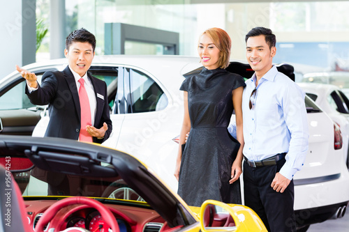 Asian couple buying car in dealership © Kzenon