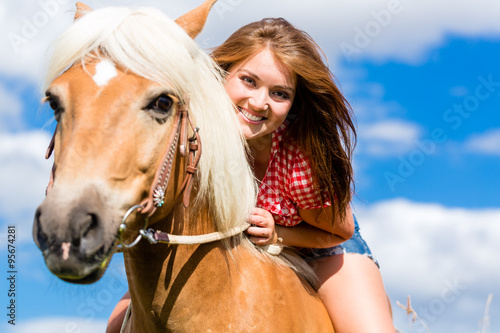 Woman riding on horse in summer meadow © Kzenon
