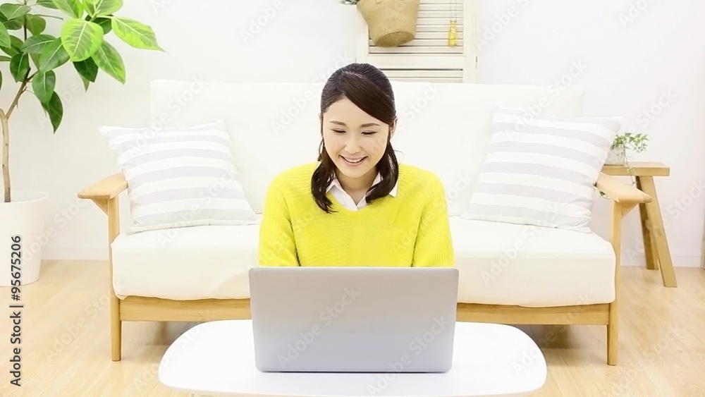 部屋でノートパソコンを使う女性