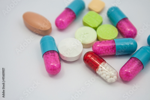 Colored pills, tablets and capsules on white background