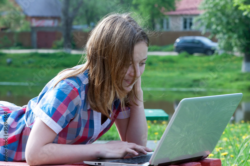 Portrait teen girl working on a laptop on a summer day outdoors photo