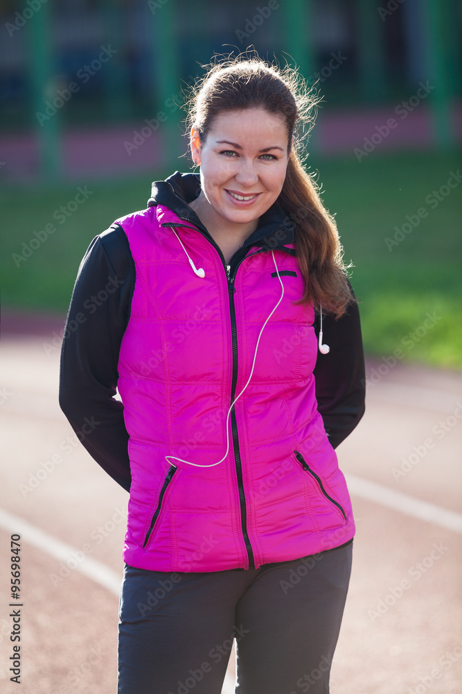 Smiling young woman portrait, standing at the stadium in sportive clothes Smiling young woman portrait, standing at the stadium in sportive clothes