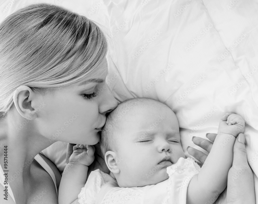Young mother and her baby, sleeping in bed. Mother and baby. Hap Young mother and her baby, sleeping in bed. Mother and baby. Hap