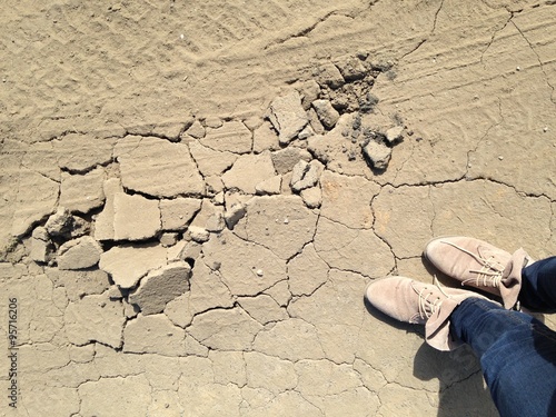 aufgeplatzter, staubiger Asphalt mit Beinen und Schuhen photo