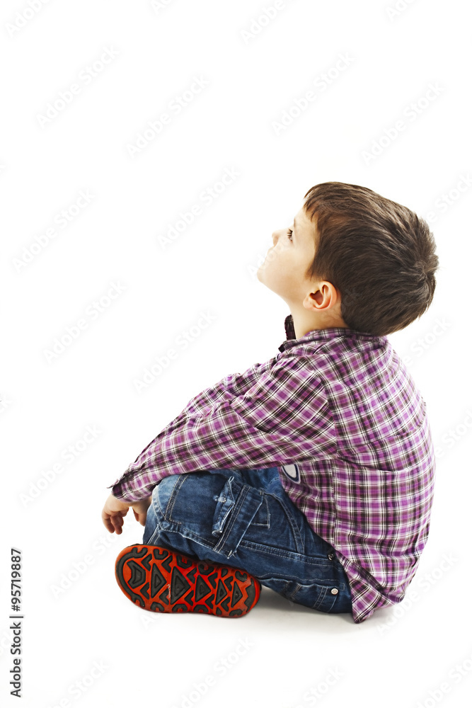 Portrait of a cute little boy sitting on the floor, looking up