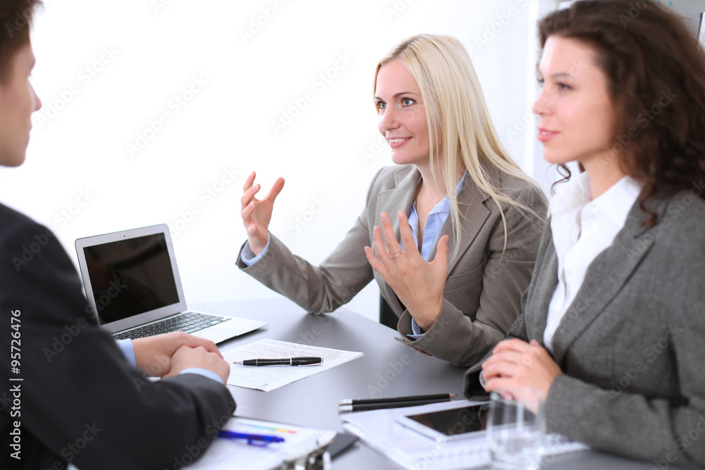 A group of business people at a meeting on the background of office. Focus on a beautiful blonde A group of business people at a meeting on the background of office. Focus on a beautiful blonde