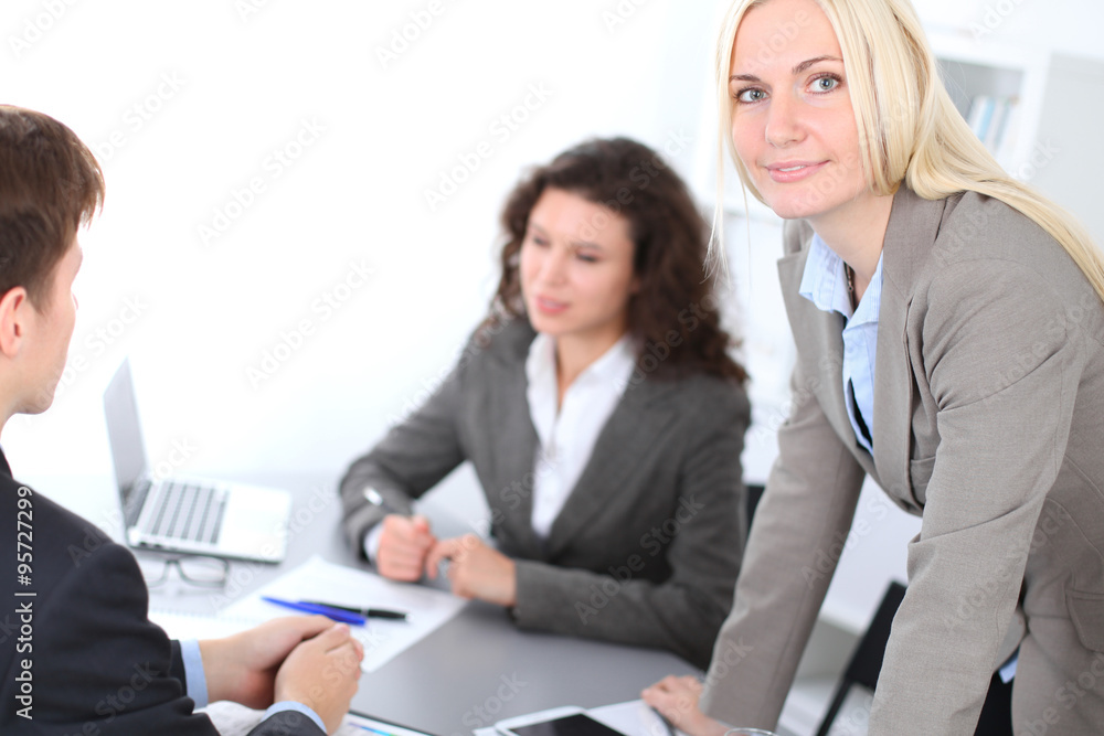 A group of business people at a meeting on the background of office. Focus on a beautiful blonde A group of business people at a meeting on the background of office. Focus on a beautiful blonde