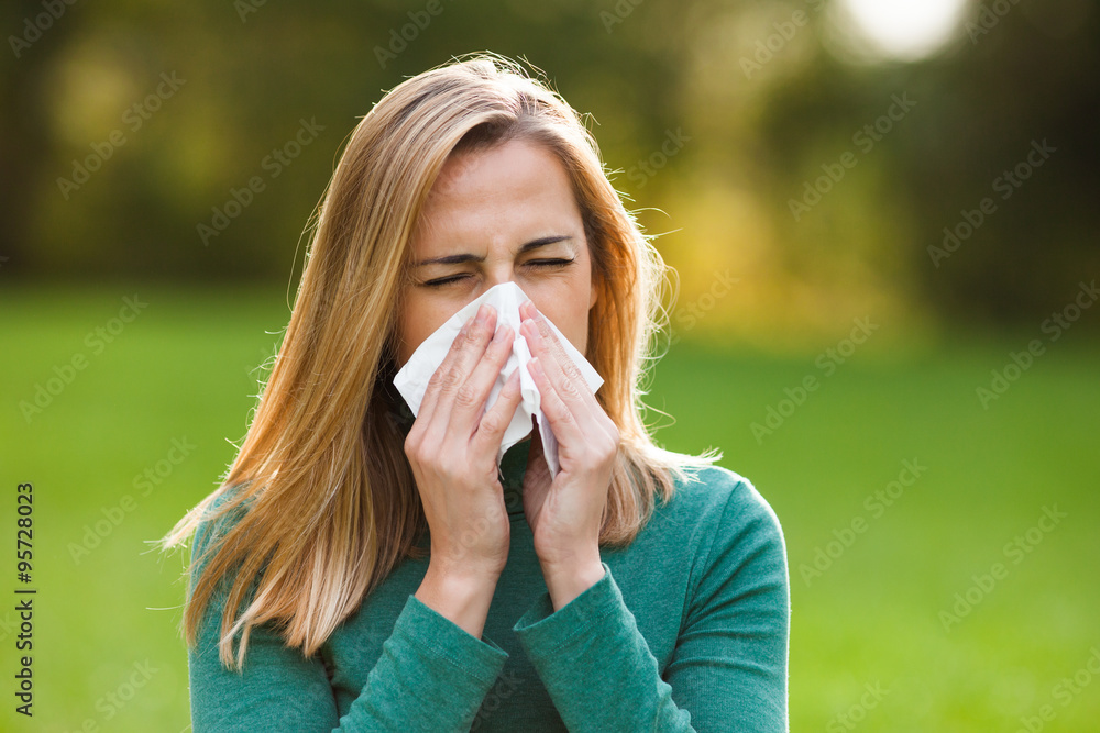 Woman with allergy symptom blowing nose Woman with allergy symptom blowing nose