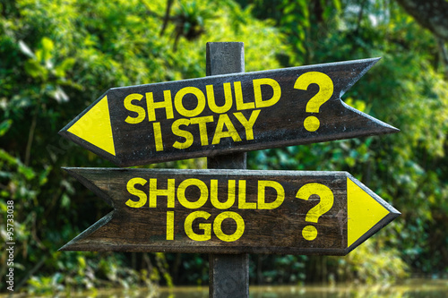 Should I Stay? Should I Go? signpost with forest background