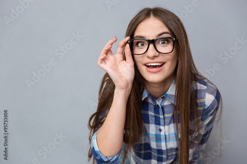 Curious cheerful woman in glasses looking at camera