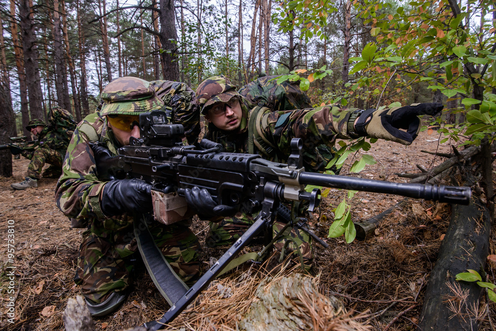Fototapeta premium Soldier demonstrates target to gunner in forest/Team of armed soldiers in uniform preparing to open fire to enemy