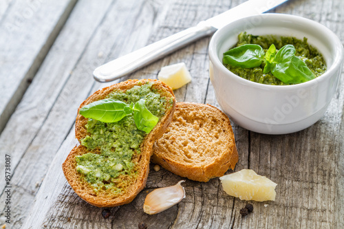 Pesto sauce in bowl, rustic wood background