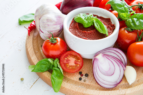Tomato sauce and ingredients on white wood background