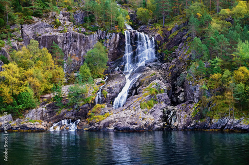 small and idyllic waterfall in the tree covered mountains surrounding Lysefjord in Norway