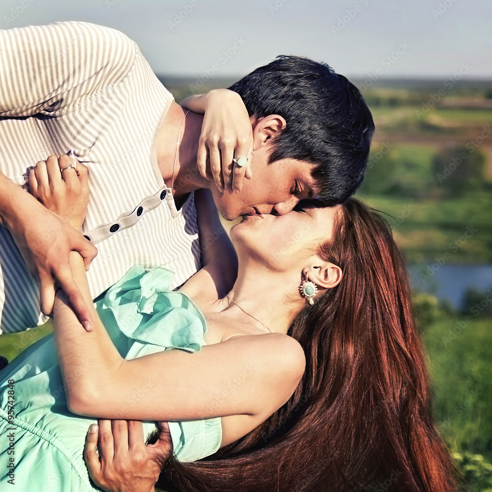 Naklejka premium summer outdoor portrait of a young couple kissing
