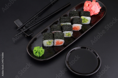 Premium quality sushi rolls with ginger wasabi and soy sauce over black background