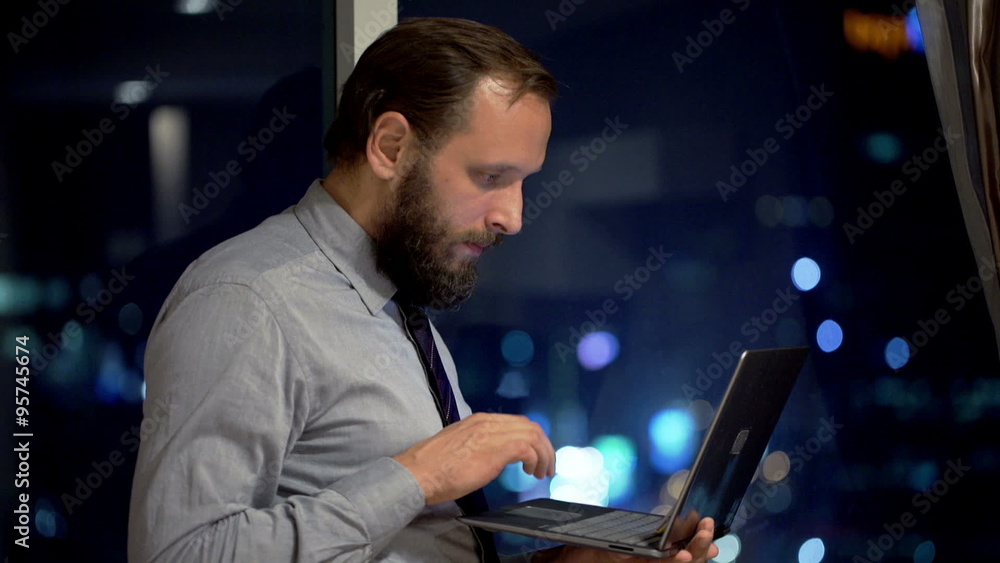 Young businessman working on laptop by window in office at night
Young businessman working on laptop by window in office at night