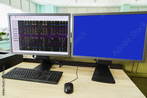 Computers and monitors with schematic diagram for supervisory, control and data acquisition in modern electrical control room