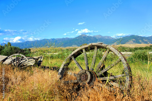 Abandoned long ago, this broken and discarded wagon, sits overgrown with weeds in Paradise Valley, Montana.  Wagon faces the Absaroka Mountains. photo