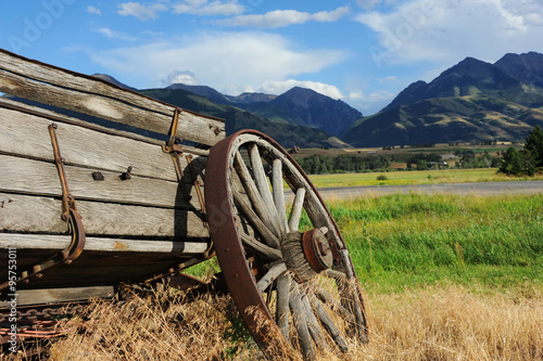 Broken down wagon is being overtaken by weeds.  Wagon sits with a beautiful view of the Absaroka Mountains in Paradise Valley, Montana. photo