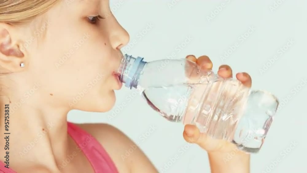 Extreme closeup portrait cute girl child drinking water from bottle at camera Extreme closeup portrait cute girl child drinking water from bottle at camera