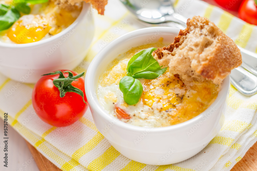 Egg cocotte in white ramekin with tomato and basil Egg cocotte in white ramekin with tomato and basil