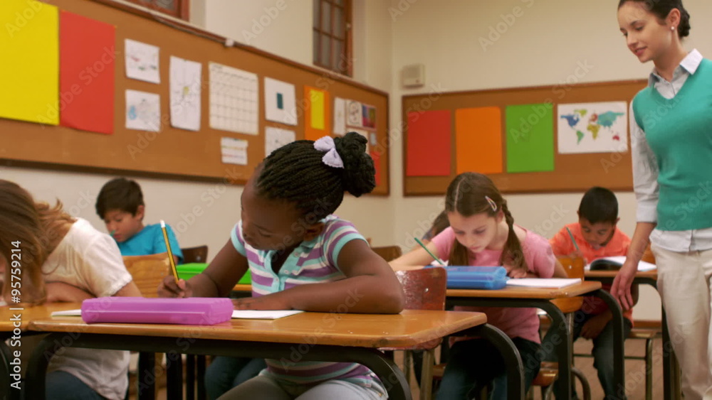 Pretty young teacher monitoring her young students Pretty young teacher monitoring her young students