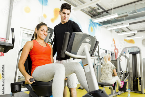Beautiful young woman instructed by a handsome man in a gym