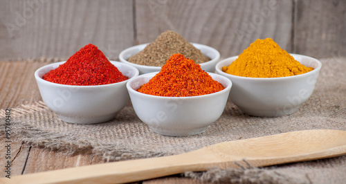 Spices in bowls on wooden background