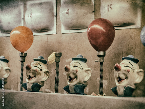 Clown Water Gun Game Vintage. Classic water gun clown balloon carnival game. Old, aged looking clown heads and numbered lights. Squirting, balloons inflating. Edited with a vintage film effect.