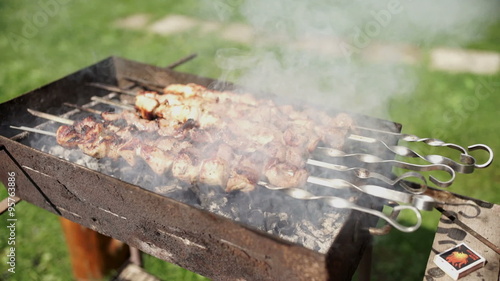 Delicious barbecue on the grill. Pieces of meat skewered on a skewer. Smoke blows around roasted kebabs and fragrant. photo