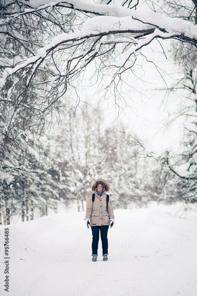 A girl wearing warm winter clothes in winter, gloomy forest. Retro filtered look.