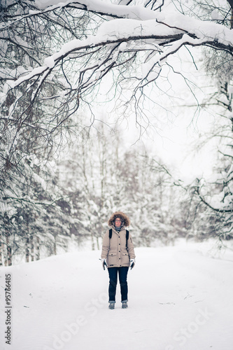 A girl wearing warm winter clothes in winter, gloomy forest. Retro filtered look.