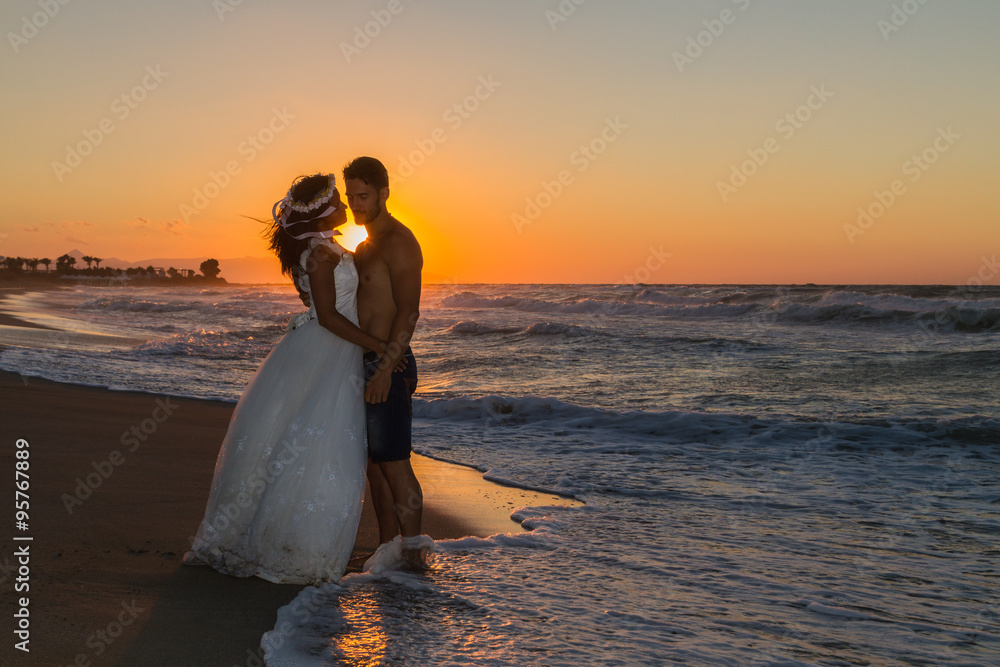 Newly wed young couple on a hazy beach at dusk.