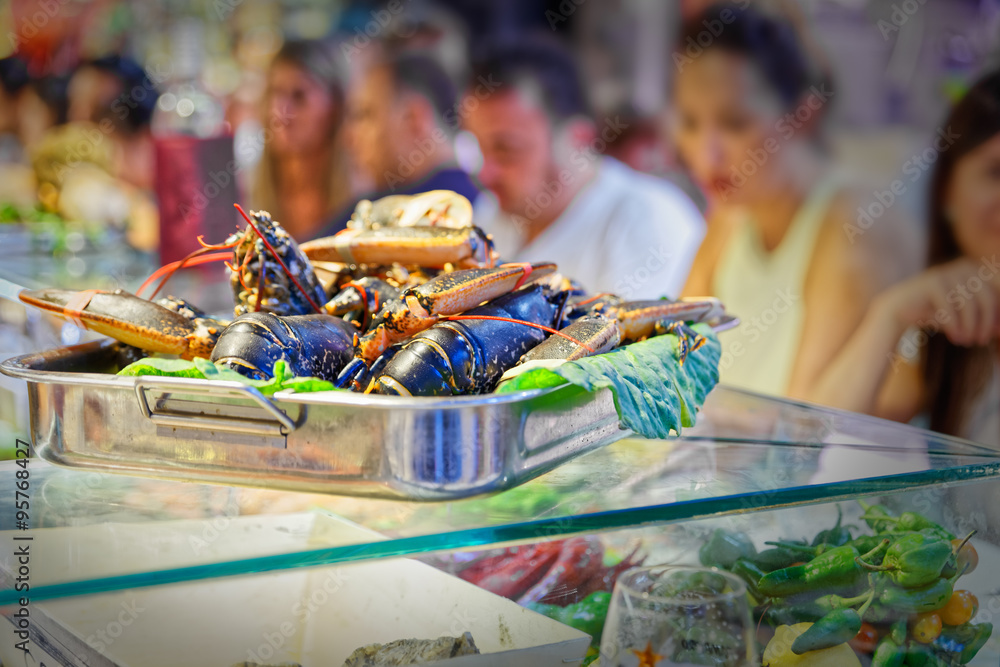 Fototapeta premium Tray on top of lobsters, in blurry background hungry people