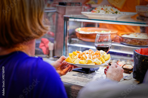 A woman picks up her first dish ready in a market stall photo