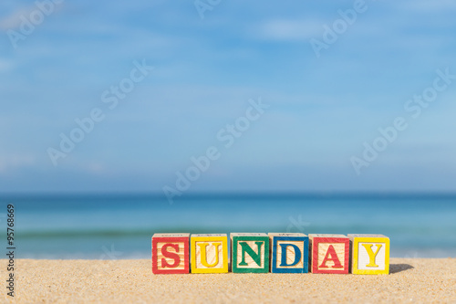 word SUNDAY in colorful alphabet blocks on tropical beach