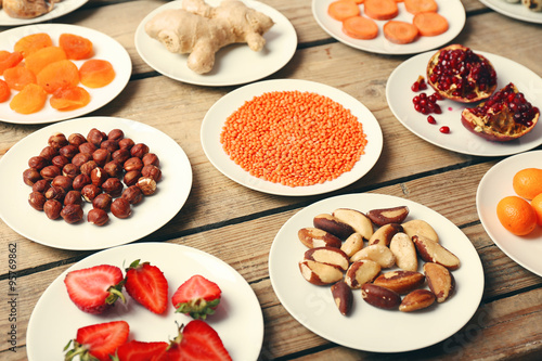 Different products on saucers on wooden table close up